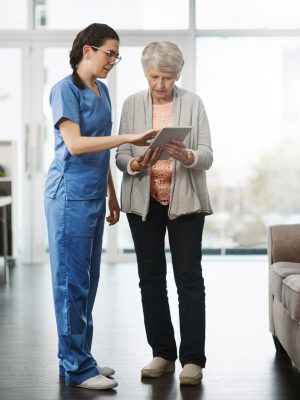 Full length shot of a young female nurse showing her senior female patient something on a digital tablet